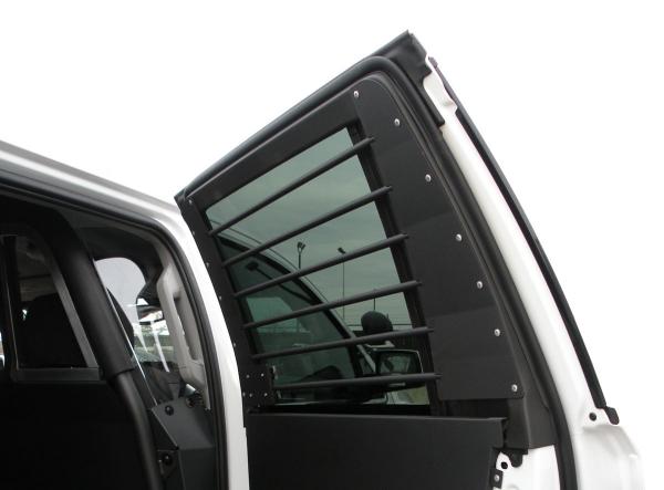 Rear door open on a white vehicle with horizontal bars across the glass and a steel panel below