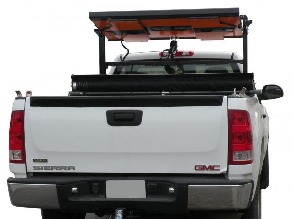 Board folded flat in its stowed position on the rack above the pickup cab, seen over the tailgate