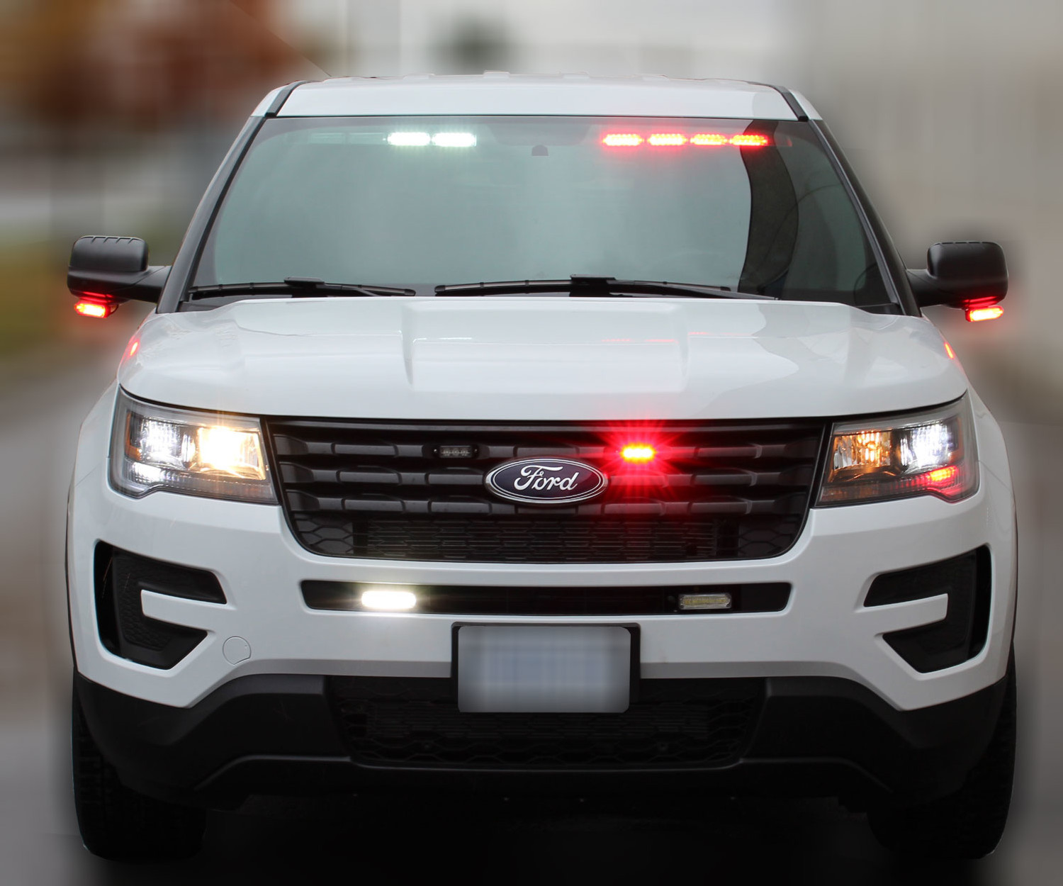 White Ford Explorer flashing red and white from the visor bar behind the windshield, with grille lights lit