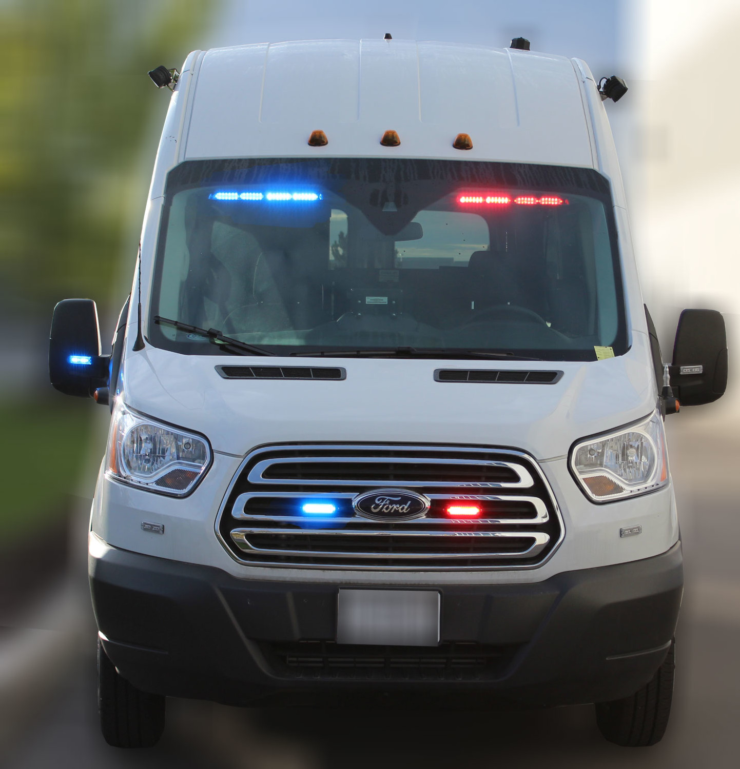 White Ford Transit van with the visor bar lit blue on the left and red on the right behind the windshield