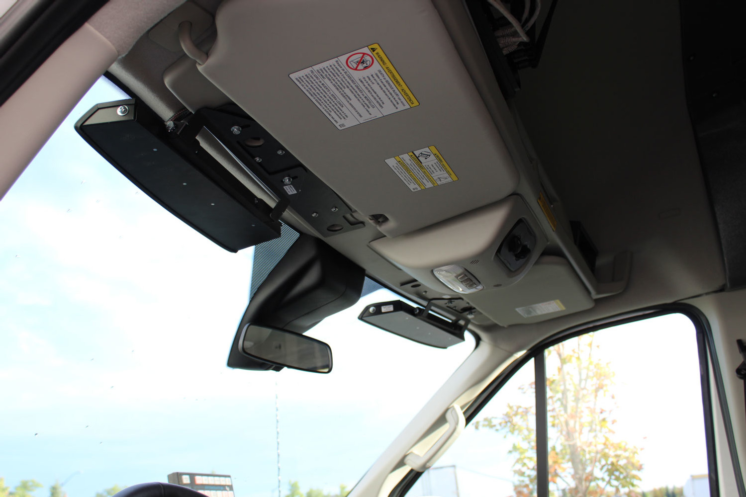 Looking up at a Transit windshield header where the black bar bracket sits beside the sun visor