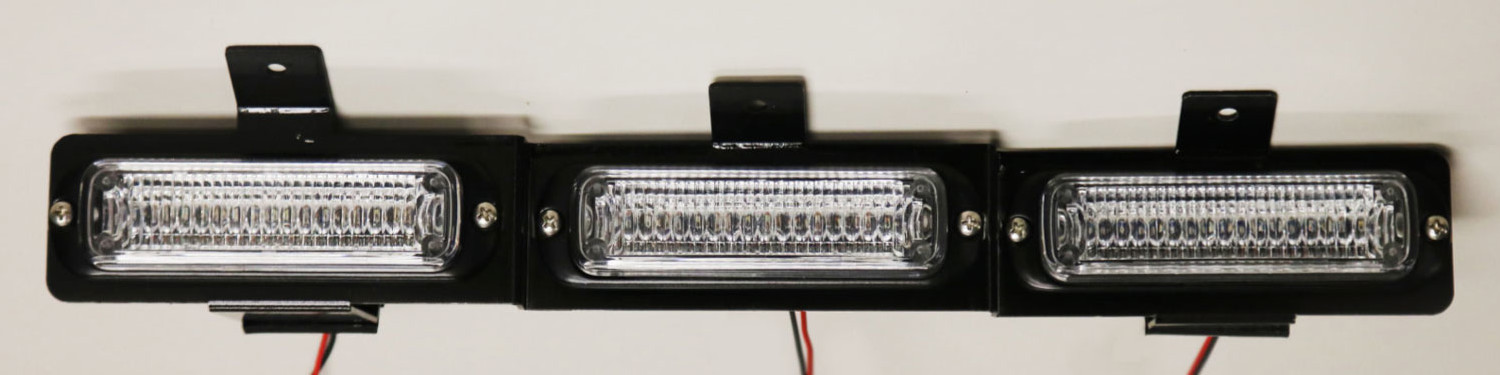 Bare three-module assembly on its black mounting bracket with wiring pigtails, straight-on and unlit