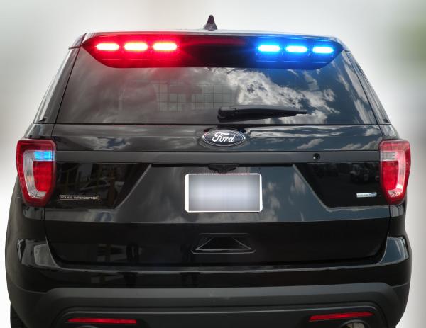 Straight-on rear of a black Explorer with the spoiler stick flashing red on the left, blue on the right